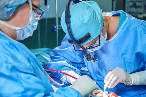 A surgeon's team in uniform performs an operation on a patient at a cardiac surgery clinic. Modern medicine, a professional team of surgeons, health. Cardiology surgeon performing a heart surgery