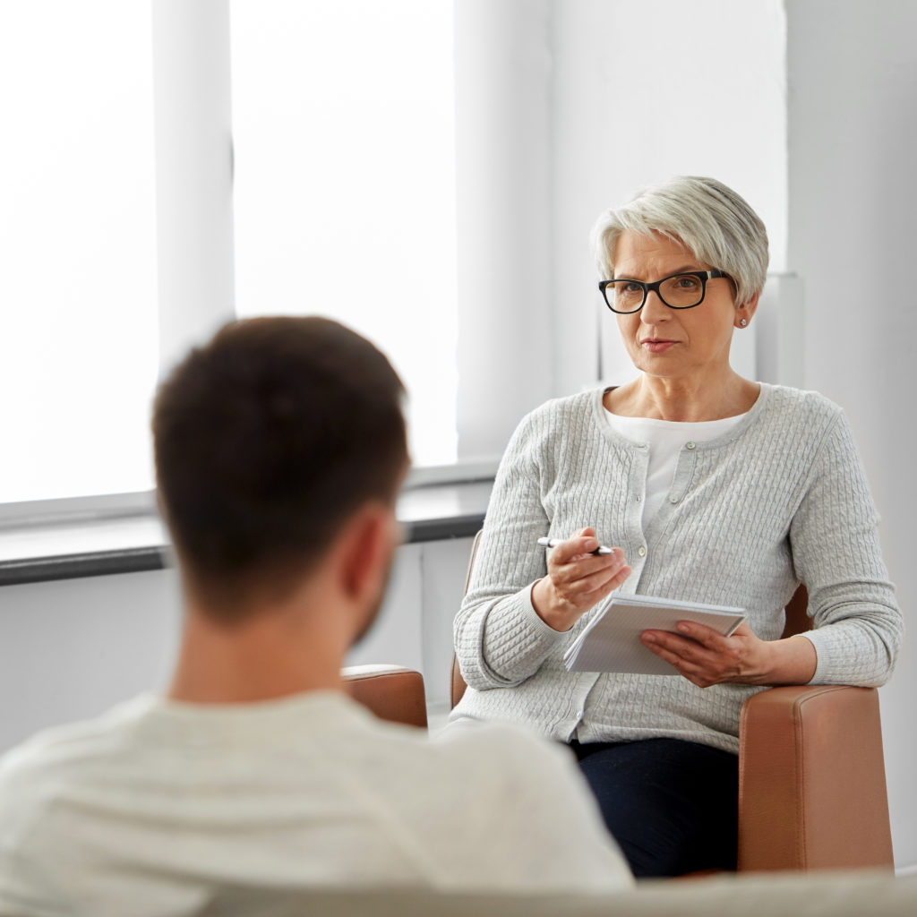 senior woman psychologist and young man patient