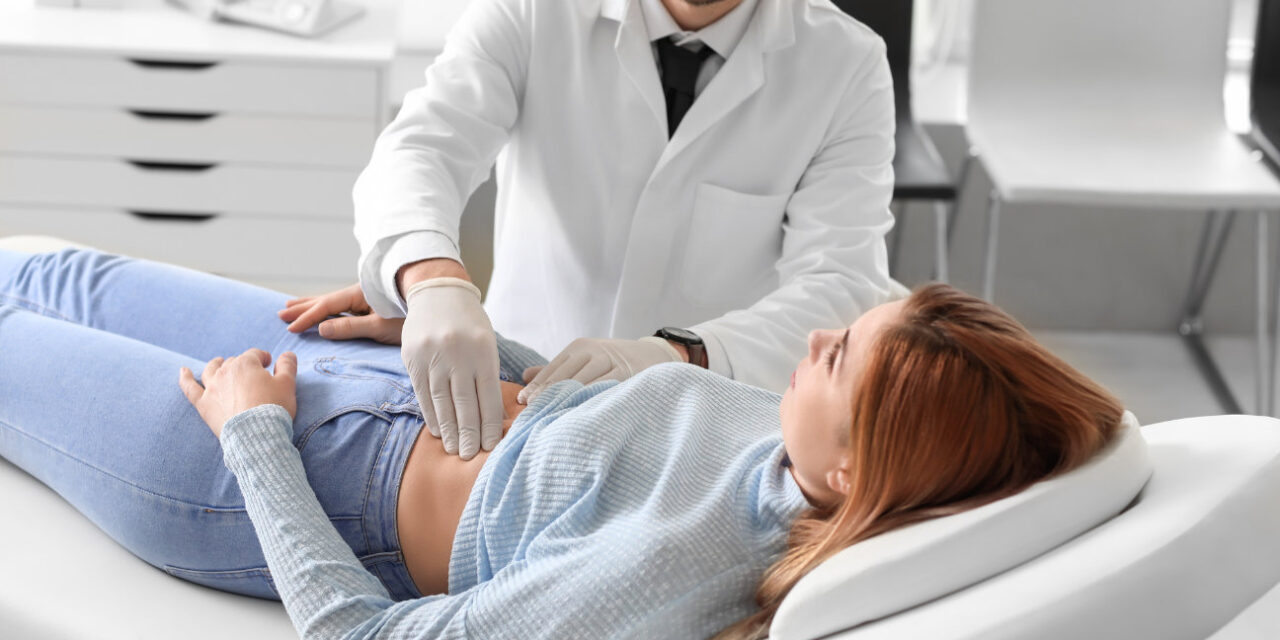 A physician checks a woman's abdomen.