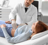 A physician checks a woman's abdomen.