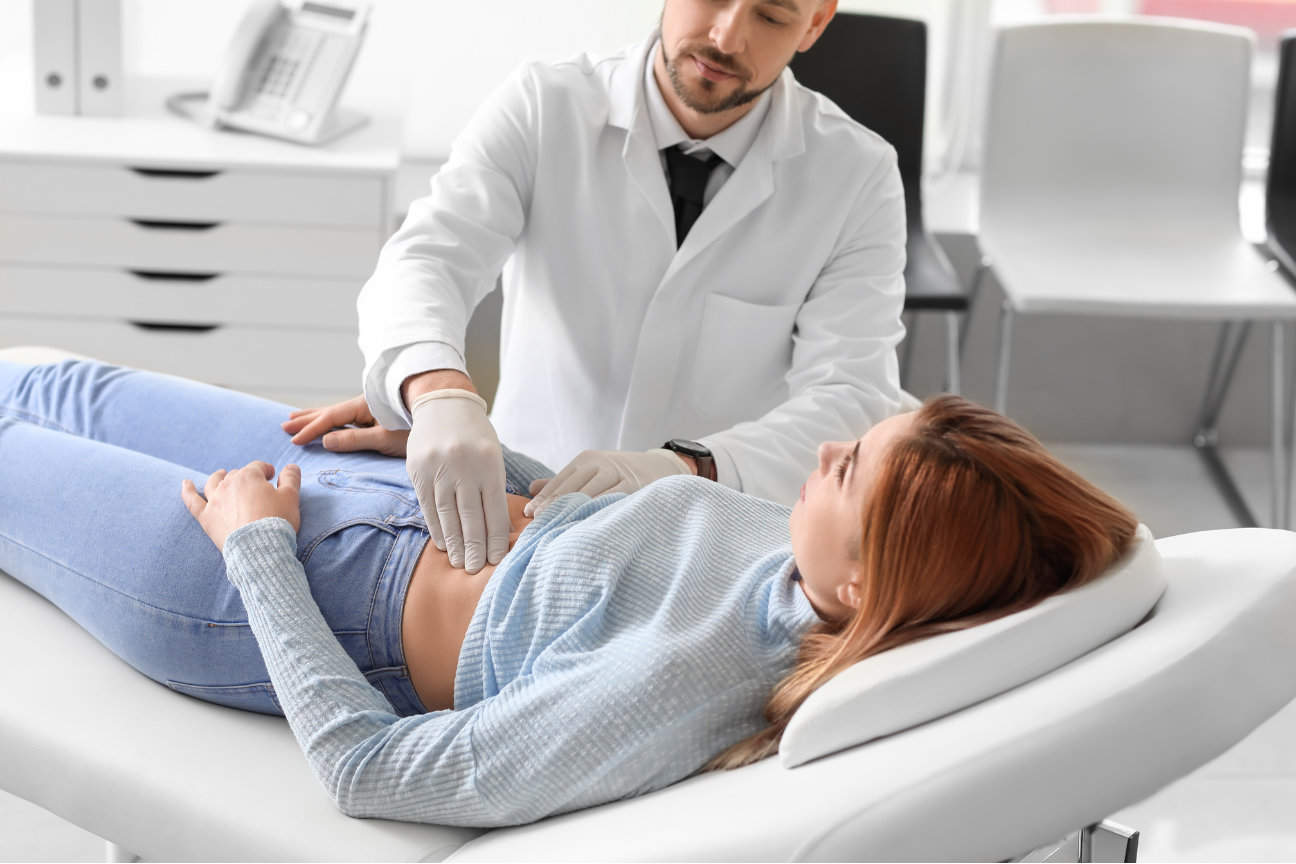 A physician checks a woman's abdomen.